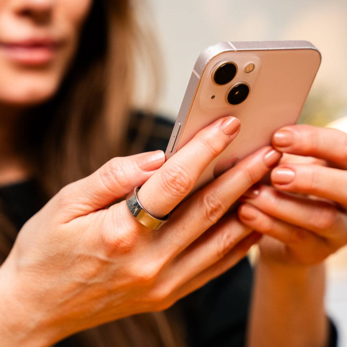 Kvinde med Luvo Ring II i sølv på fingeren, mens hun kigger på sin telefon